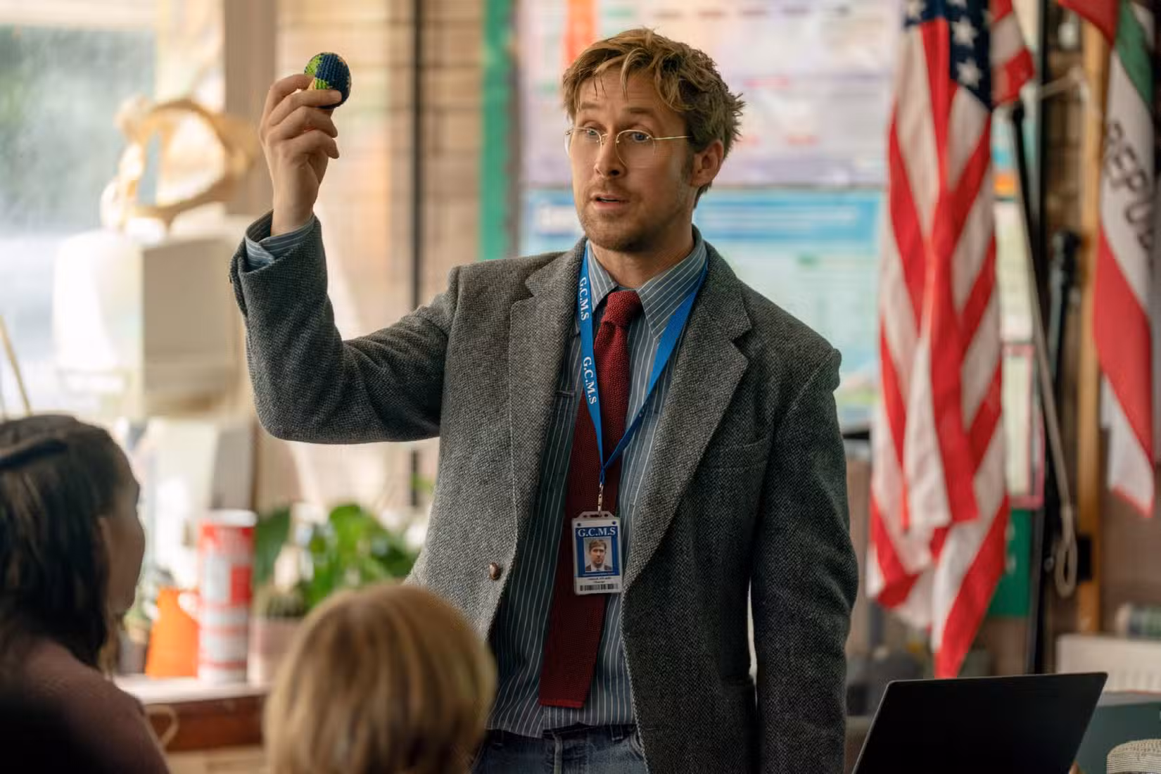 O professor de ciências do ensino médio Ryland Grace (Ryan Gosling, desgrenhado e com um paletó de tweed) segura uma bola em sua sala de aula no Projeto Ave Maria