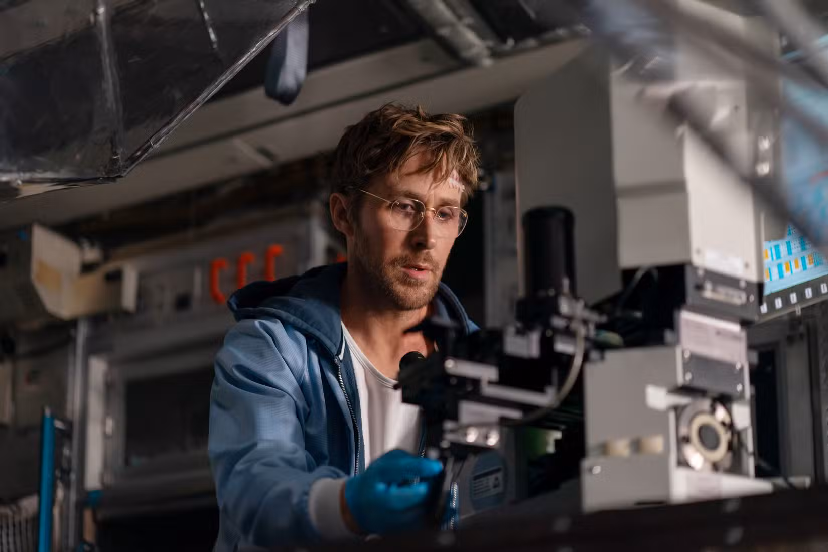 O cientista Ryland Grace (Ryan Gosling) senta-se em frente a um microscópio de alta tecnologia no Projeto Ave Maria