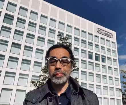 um homem de óculos em frente ao prédio da sede da Nintendo em formato de bloco 
