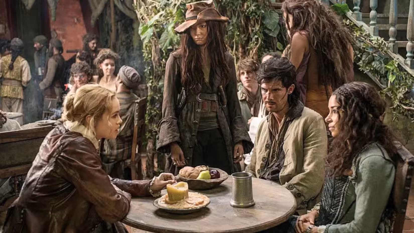 Uma imagem apresentando Hannah New como Eleanor Guthrie e Jessica Parker Kennedy como Max. Eles se juntam a Clara Paget como Anne Bonny e Toby Schmitz como Jack Rackham. Juntos, os quatro sentam-se à mesa, parecendo tensos e concisos.