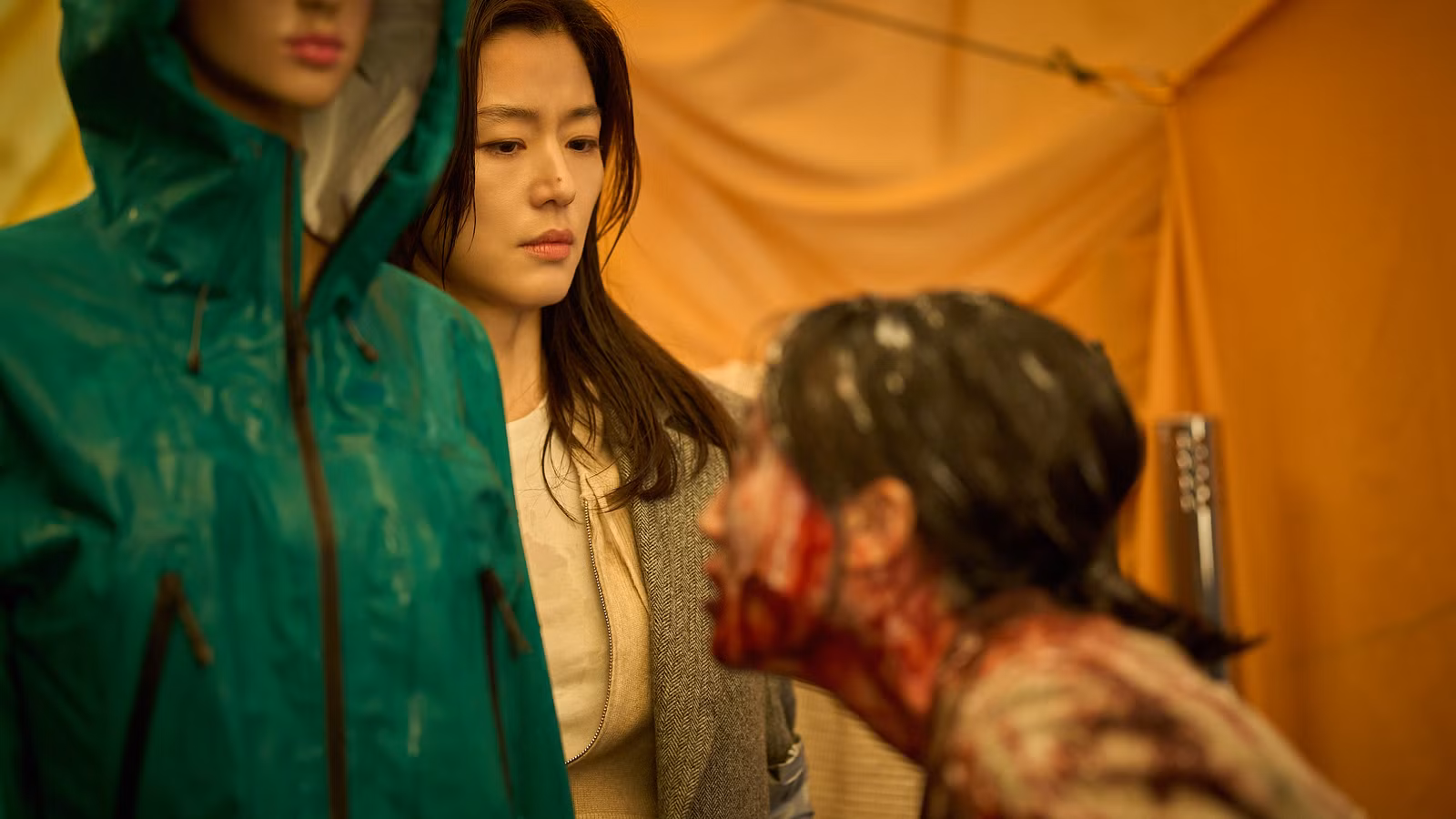 Uma mulher coreana de aparência assustada tenta manter a emoção longe de seu rosto enquanto um humanóide coberto de sangue a fareja na Colônia