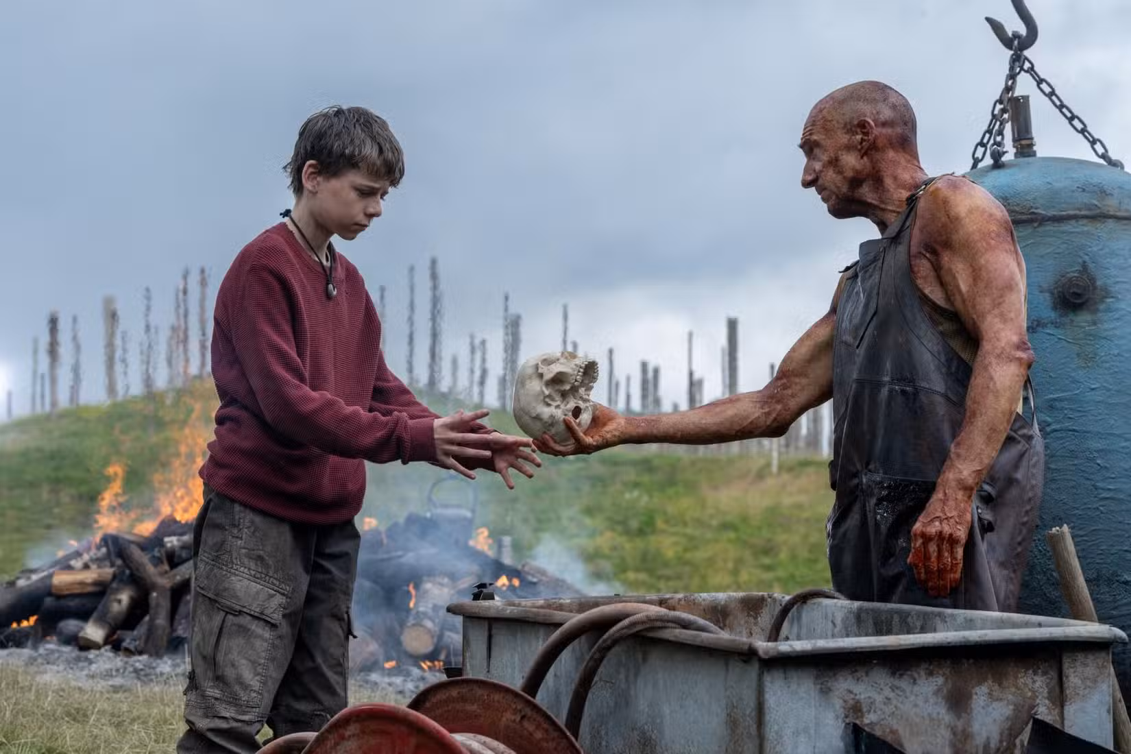 Spike, de 12 anos, examina uma caveira apresentada por um estranho misterioso interpretado por Ralph Fiennes em uma cena de 28 anos depois