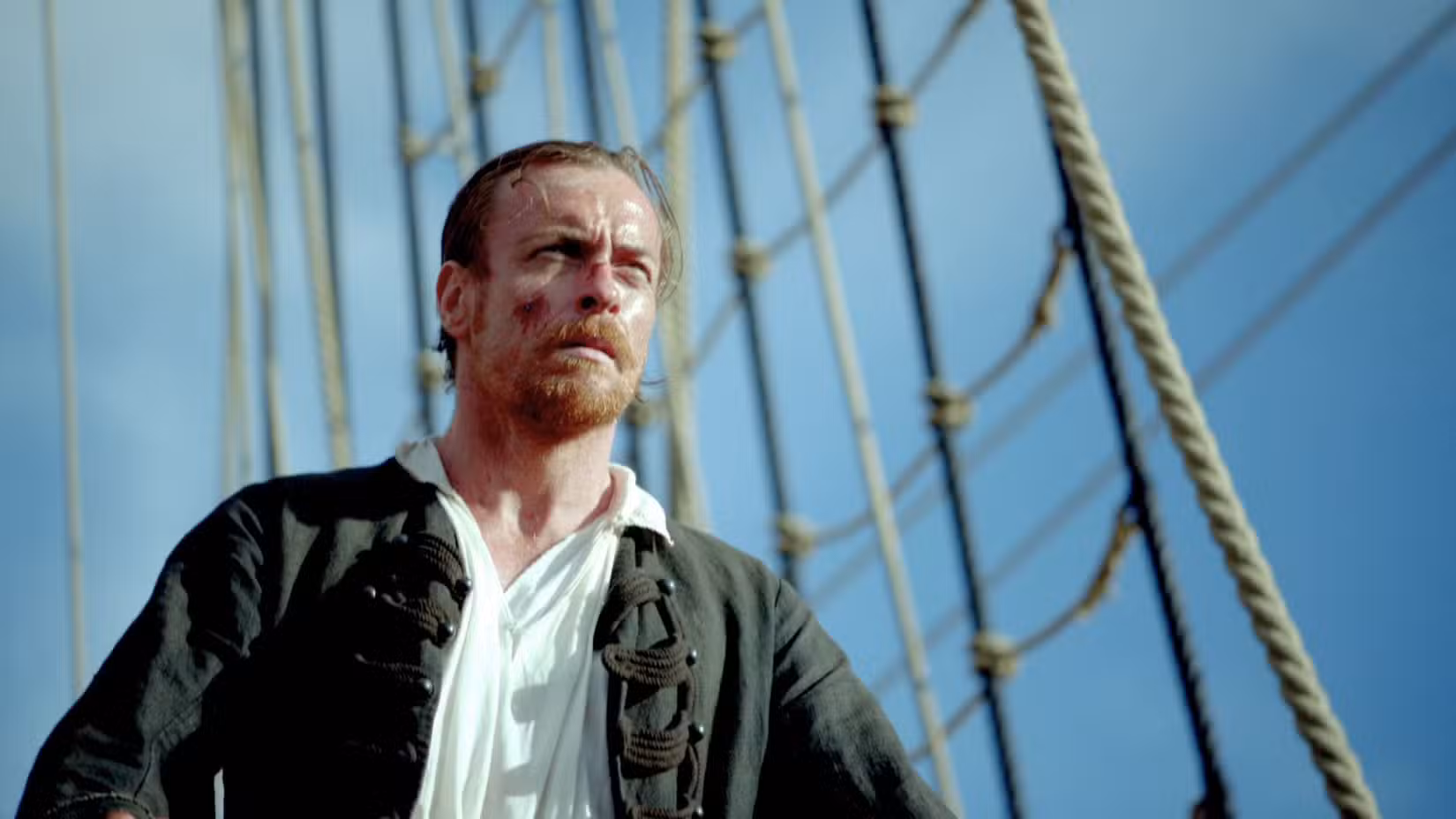 James Flint (Toby Stephens) está ensanguentado e machucado. Seu cabelo está preso em um rabo de cavalo curto e ele tem uma barba e cavanhaque majestosos. Ele parece robusto e cansado.