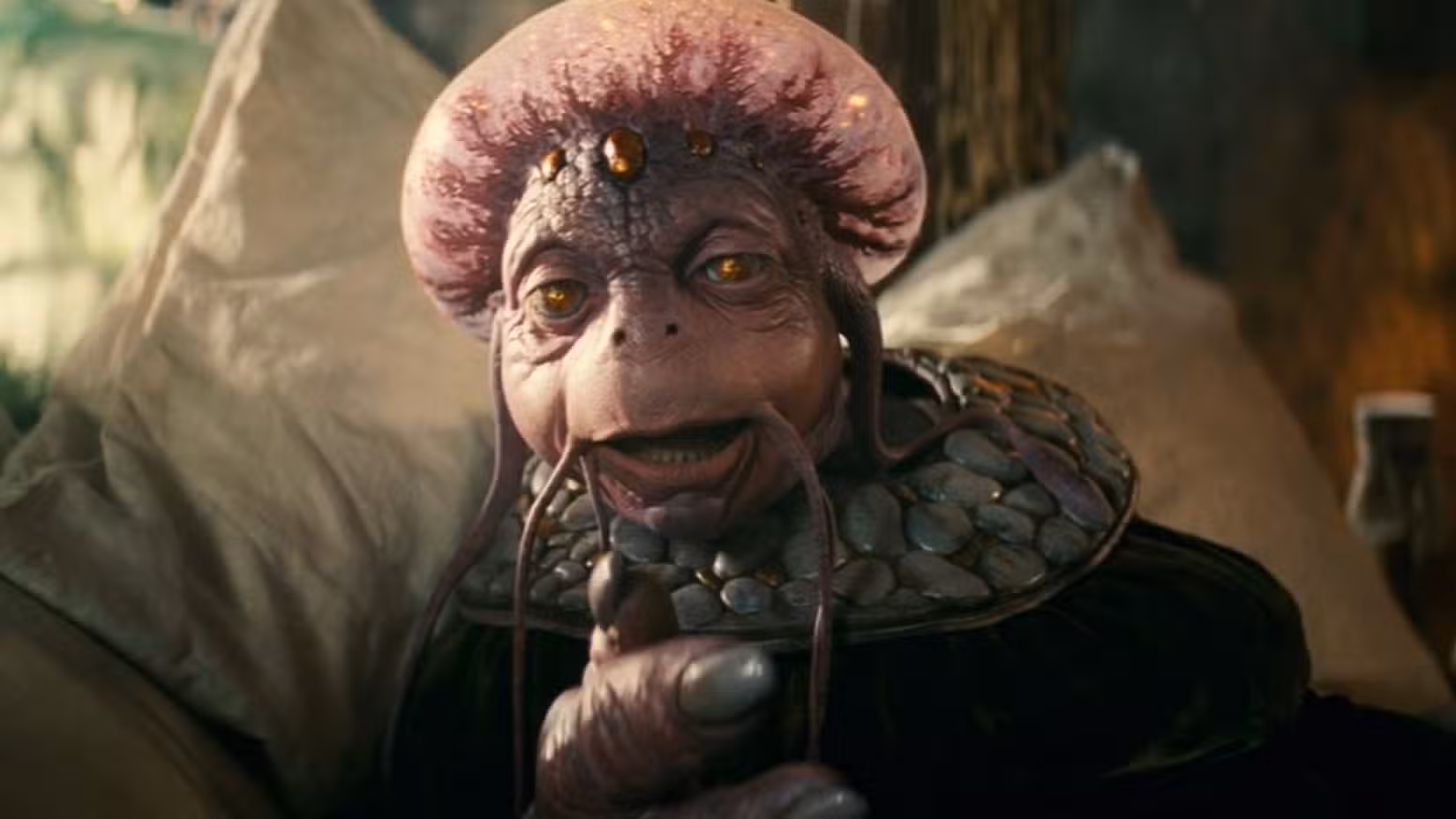 Um boneco humanóide parecido com um lagarto, com olhos vidrados e cabeça protuberante, reclina-se em sua cama em uma cena da comédia de fantasia de 2011, Sua Alteza