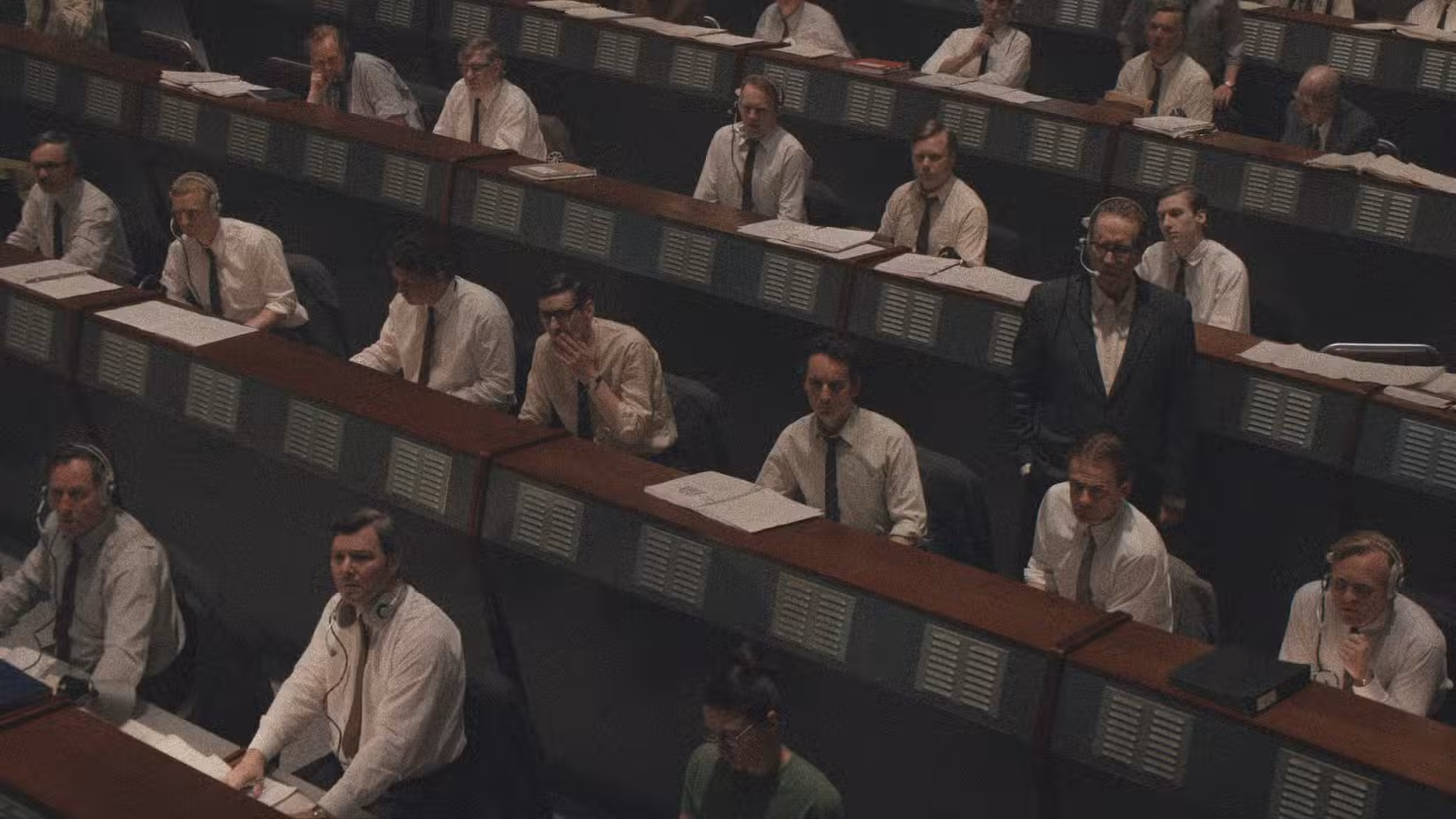 Um grupo de homens vestindo camisas brancas e gravatas e fones de ouvido na sala de comando do programa espacial soviético em Star City