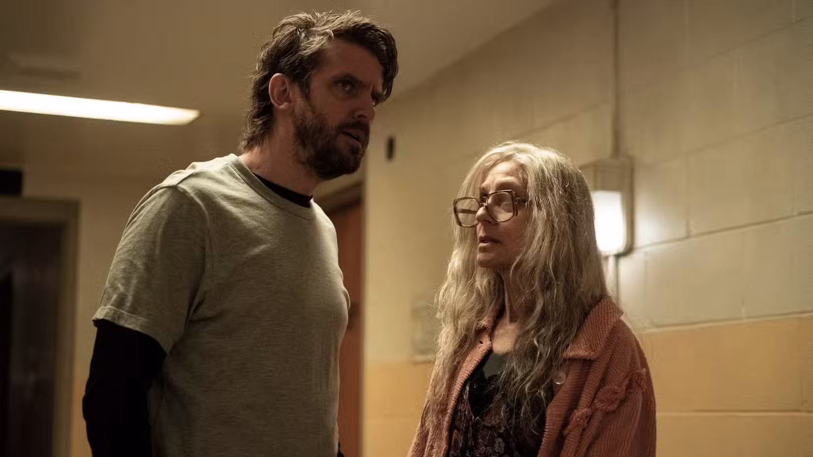 Pepper (Dan Stevens) olha para um corredor parecendo nervoso enquanto Dorry (Judith Light) olha para ele.