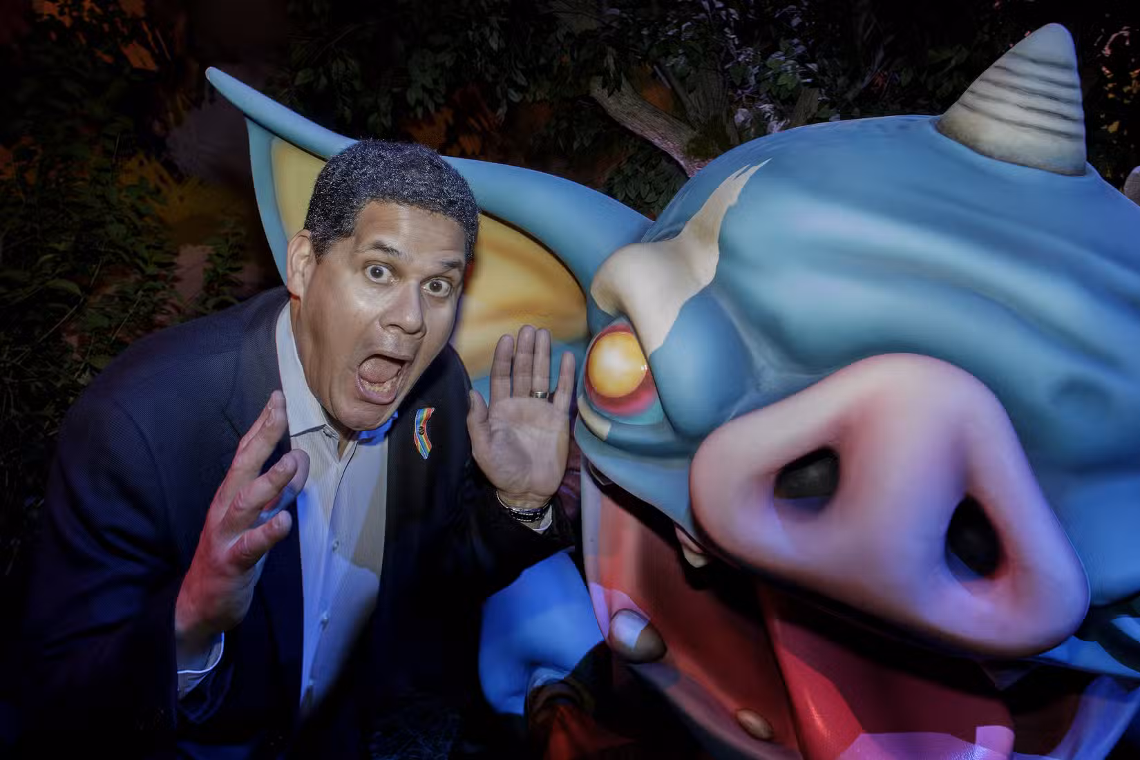 Reggie Fils-Aime faz uma careta engraçada ao lado de uma estátua enorme de um bokoblin, uma criatura de desenho animado de Legend of Zelda