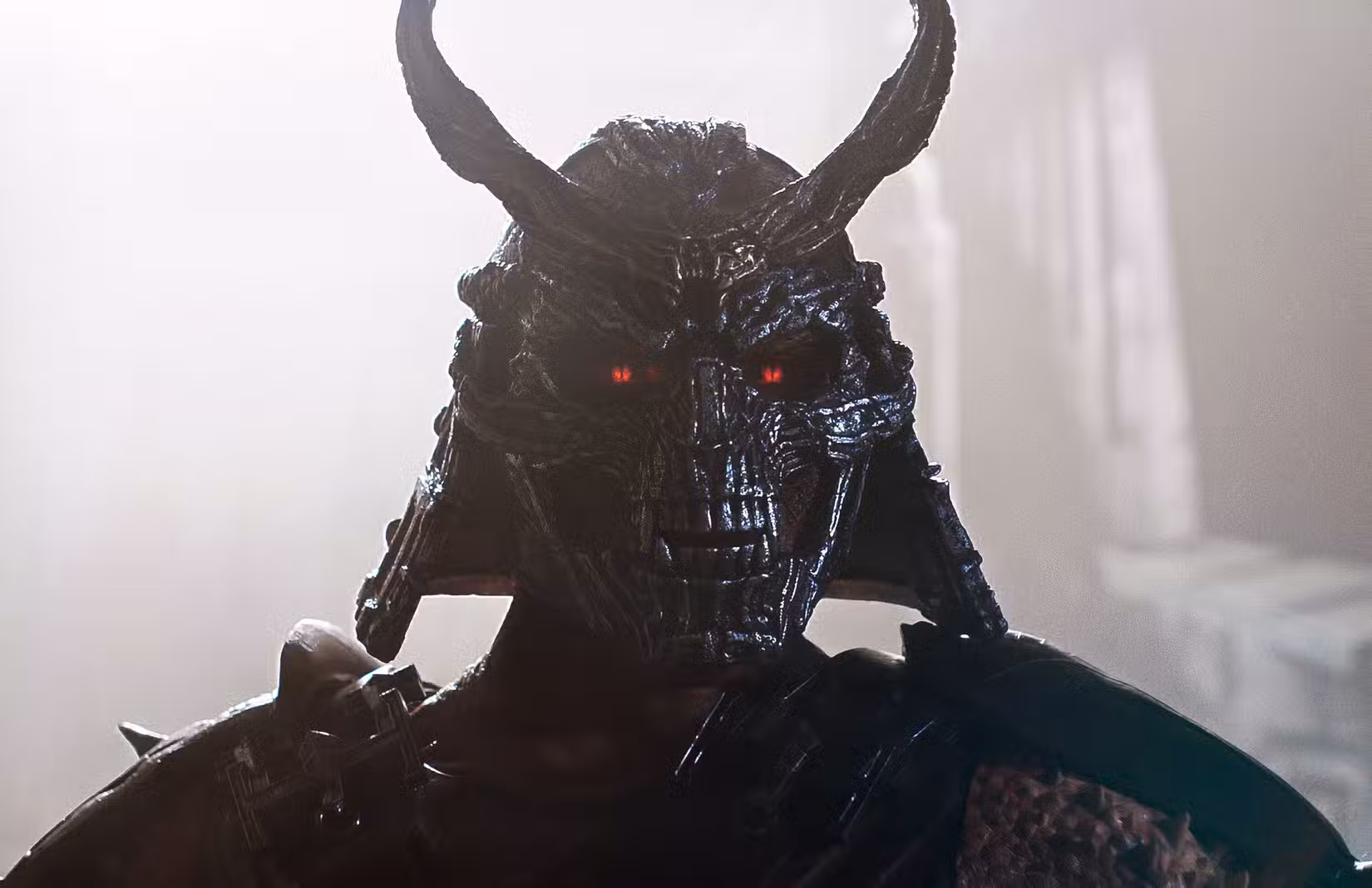 Shao Kahn (Martyn Ford) em Mortal Kombat II, uma figura blindada com olhos vermelhos brilhantes e capacete de metal cinza que combina um kabuto de samurai com uma máscara de caveira com presas. De Mortal Kombat II.