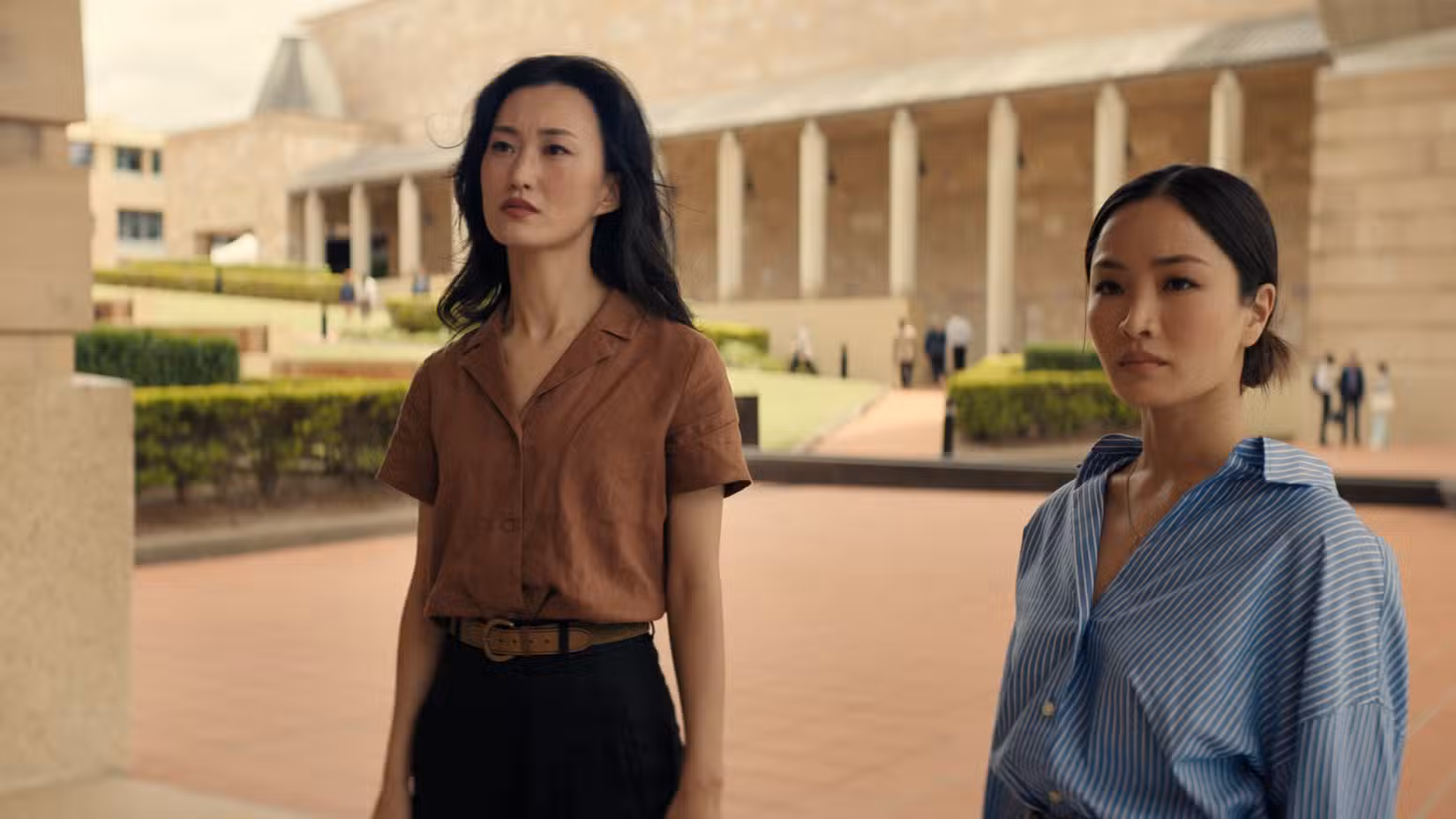 Keiko Miura (Mari Yamamoto) e Cate Randa (Anna Sawai) estão do lado de fora da sede da Monarch olhando para uma placa memorial em Monarch: Legacy of Monsters temporada 2.